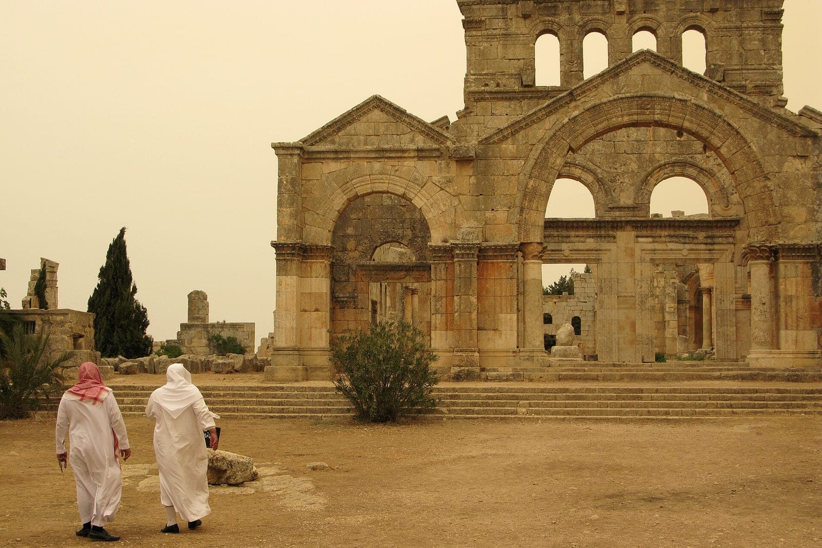 The facade of the Church of Saint Simeon Stylites, with two figures walking toward it